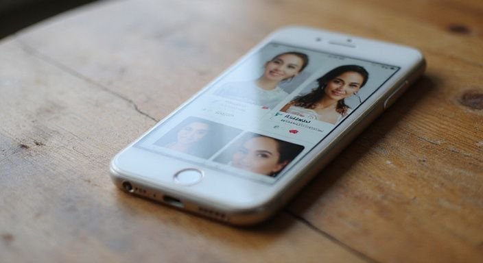 Smartphone zeigt Dating Profile auf einem hölzernen Tisch